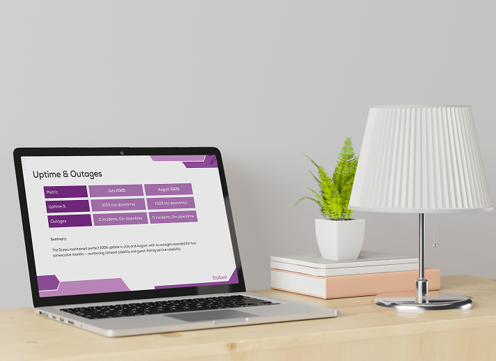 A laptop on a desk showing a purple and white 'Uptime & Outages' report with performance metrics for July and August 2025