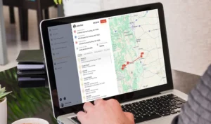 DzSense: The image depicts a person using a laptop to view a connected device monitoring application, which displays a list of statuses alongside a map showing a tracked route.